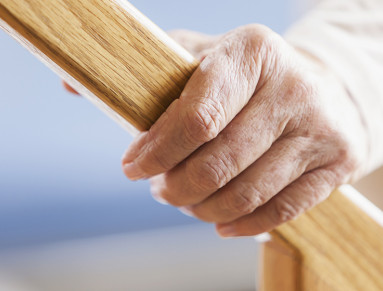 Personne âgée tenant fermement une rampe en bois