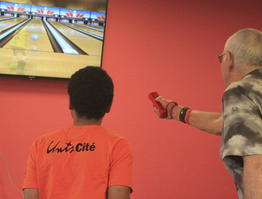 Jeune en service civique et senior jouant à Wii-Bowling