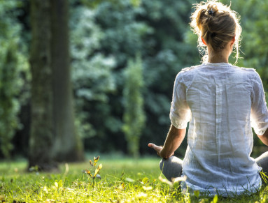Femme qui médite assise dans l'herbe