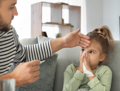 Un père pose la main sur le front de son enfant pour vérifier sa température.