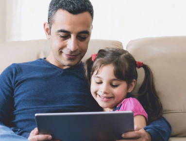 Un père lit une histoire à sa fille sur une tablette.