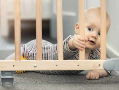 Un enfant en bas âge s’approche des marches de l’escalier, protégé par une barrière.