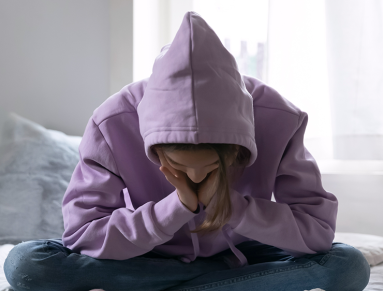 Une adolescente déprimée, assise seule sur son lit