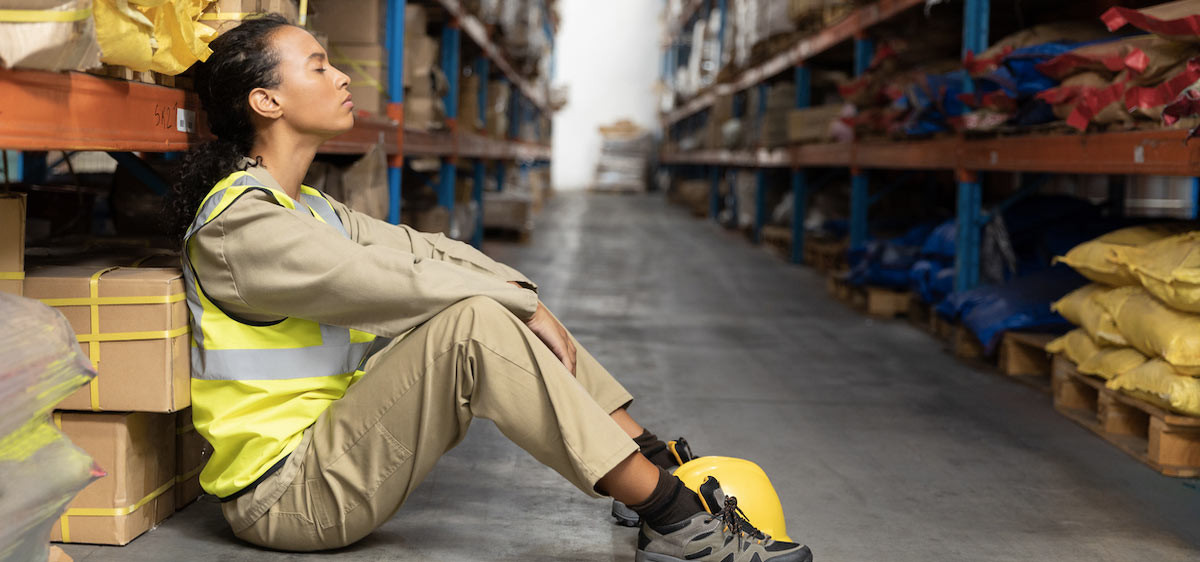 Une jeune femme est assise sur le sol dans un entrepôt.