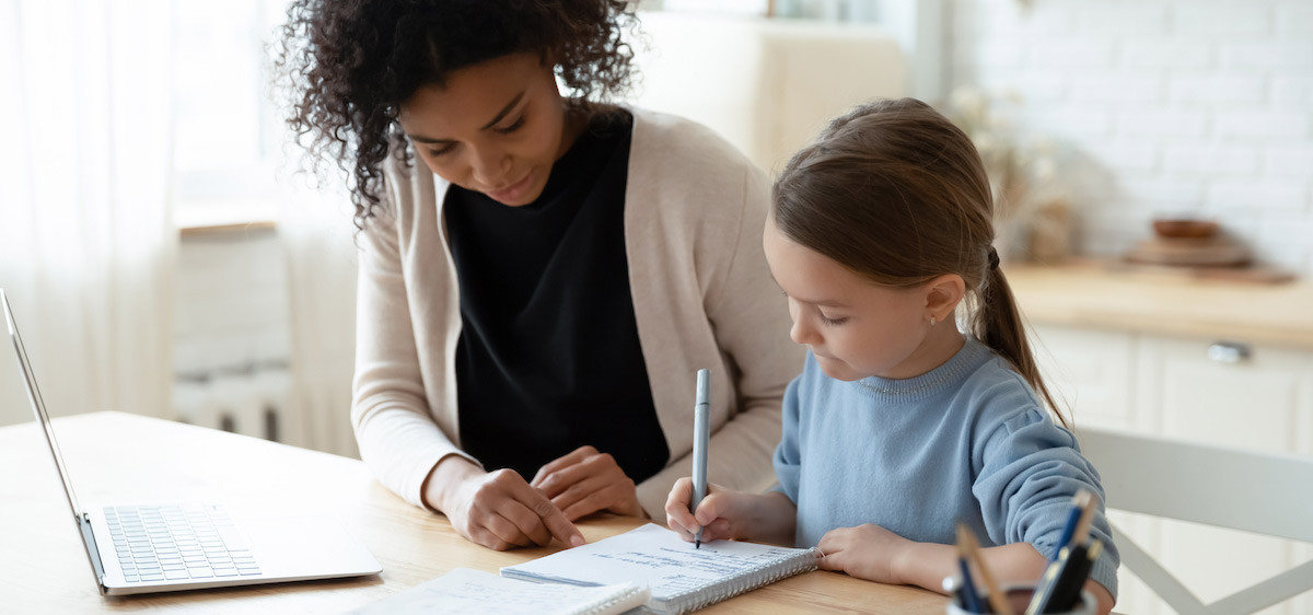 Une bénévole aide une enfant à faire ses devoirs.