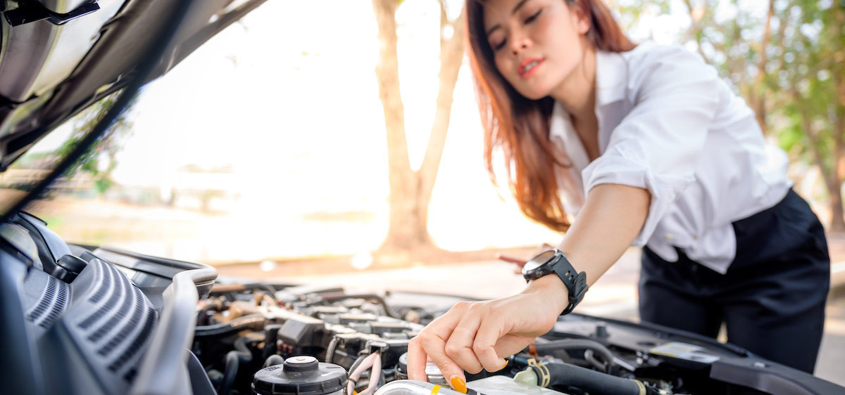 Une femme vérifie le niveau d’huile moteur de sa voiture.