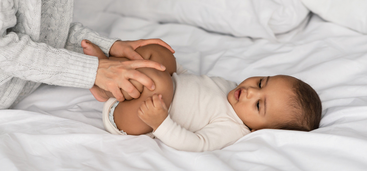 Une maman pose la main sur le ventre de son bébé pour soulager les troubles digestifs de bébé.