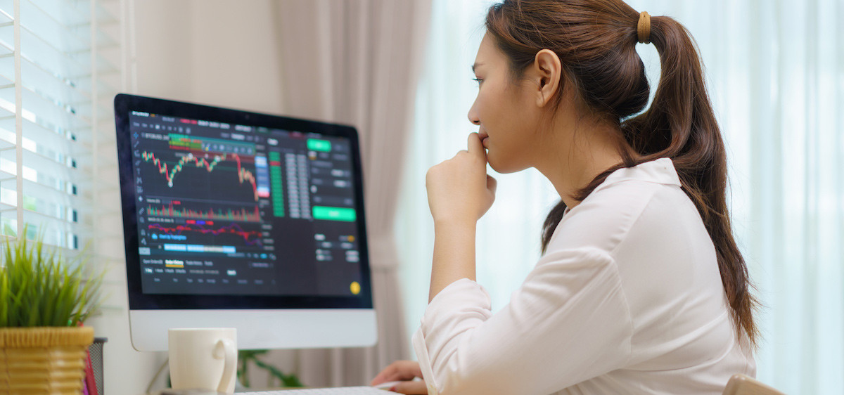 Une femme devant son ordinateur investit dans de la crypto-monnaie.