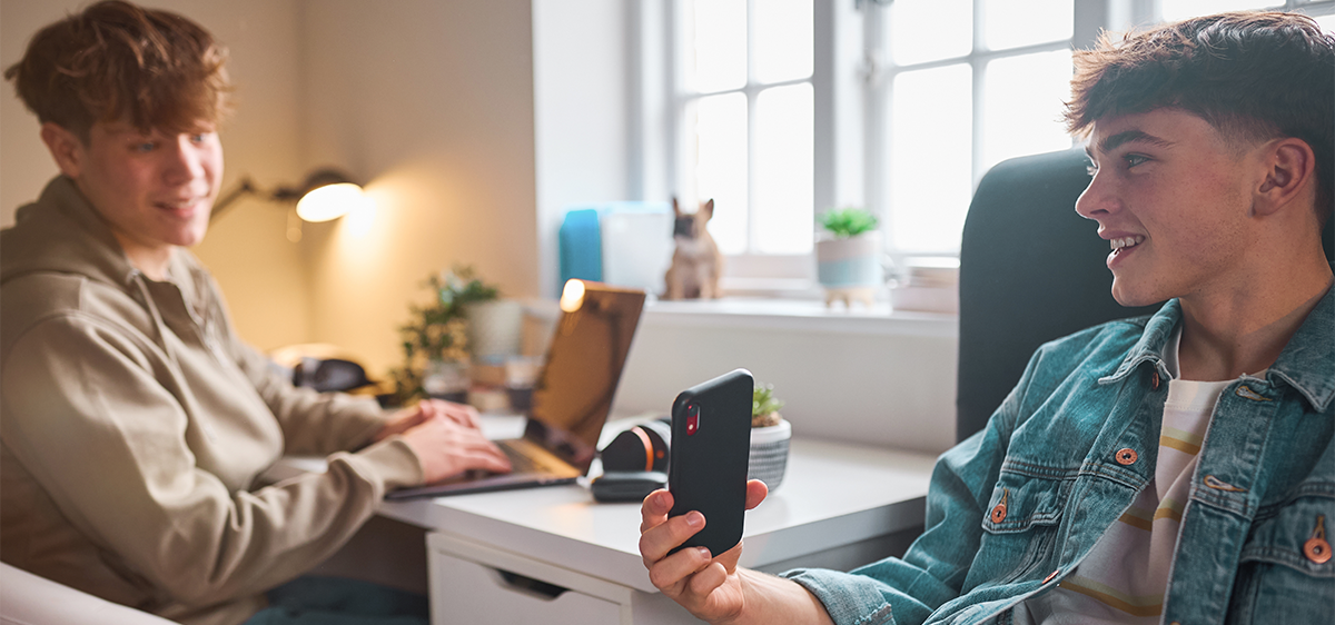 Deux adolescents se montrent leur téléphone.