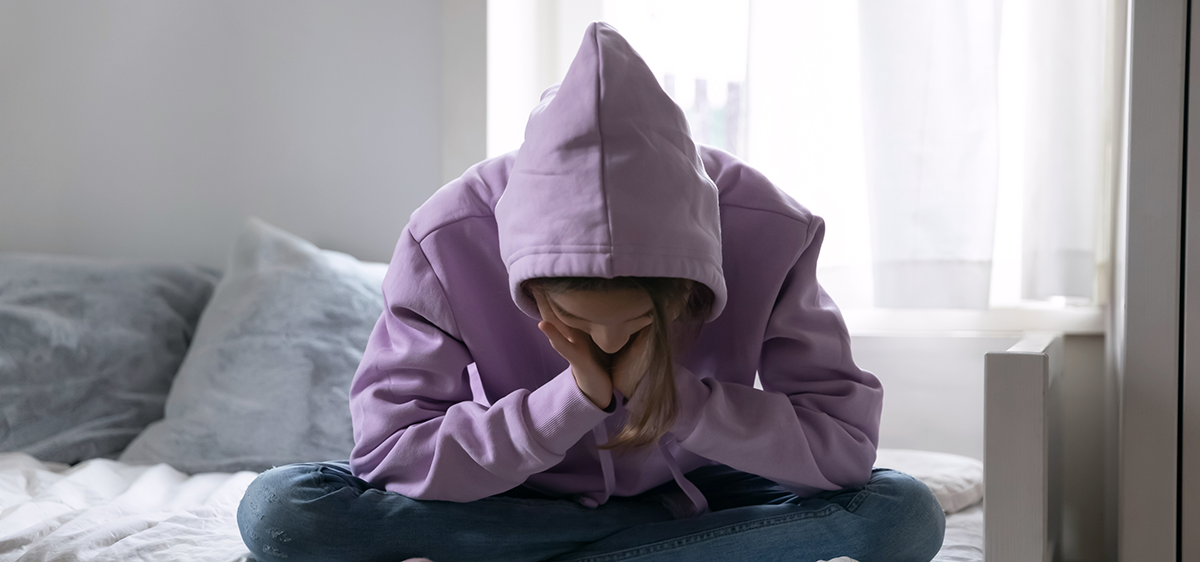 Une adolescente déprimée, assise seule sur son lit